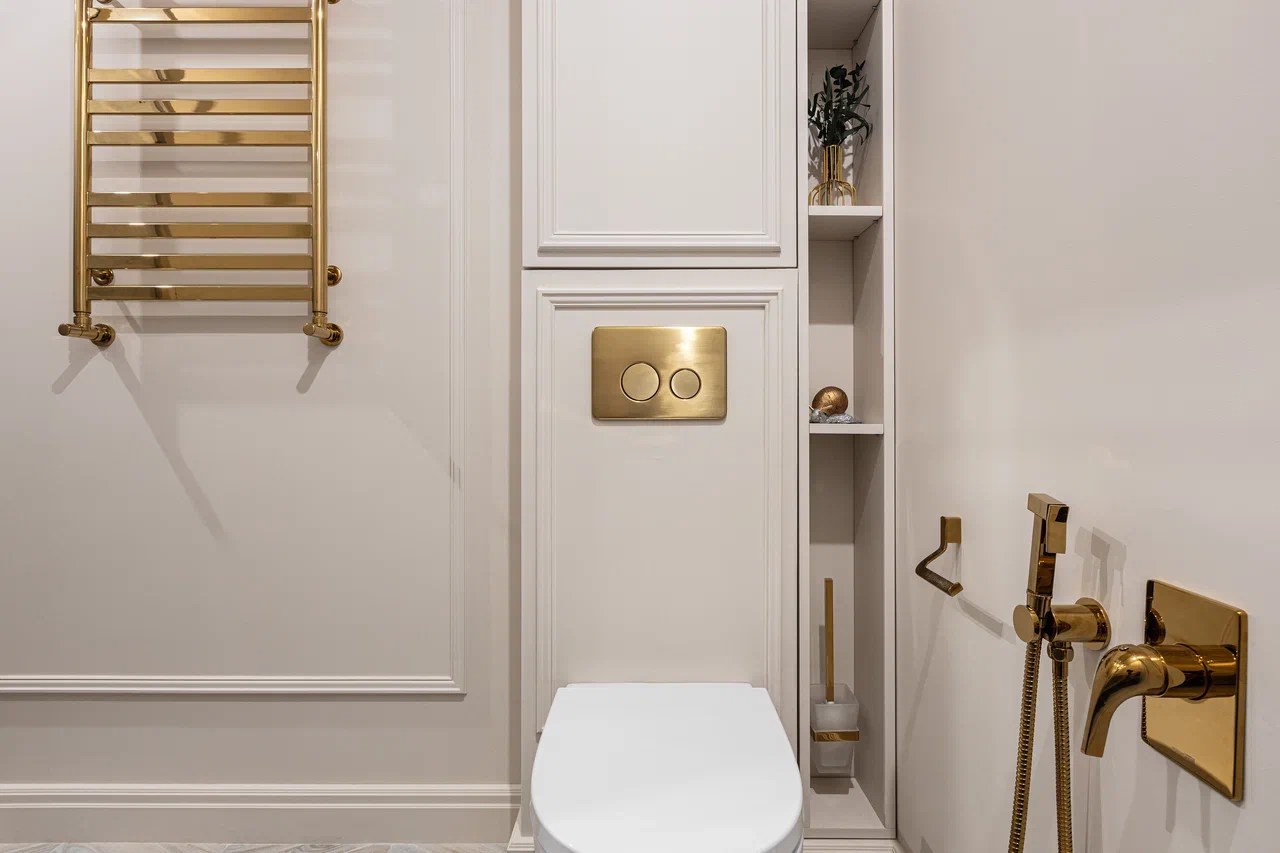 Light paneled bathroom with brass fixtures and recessed shelving