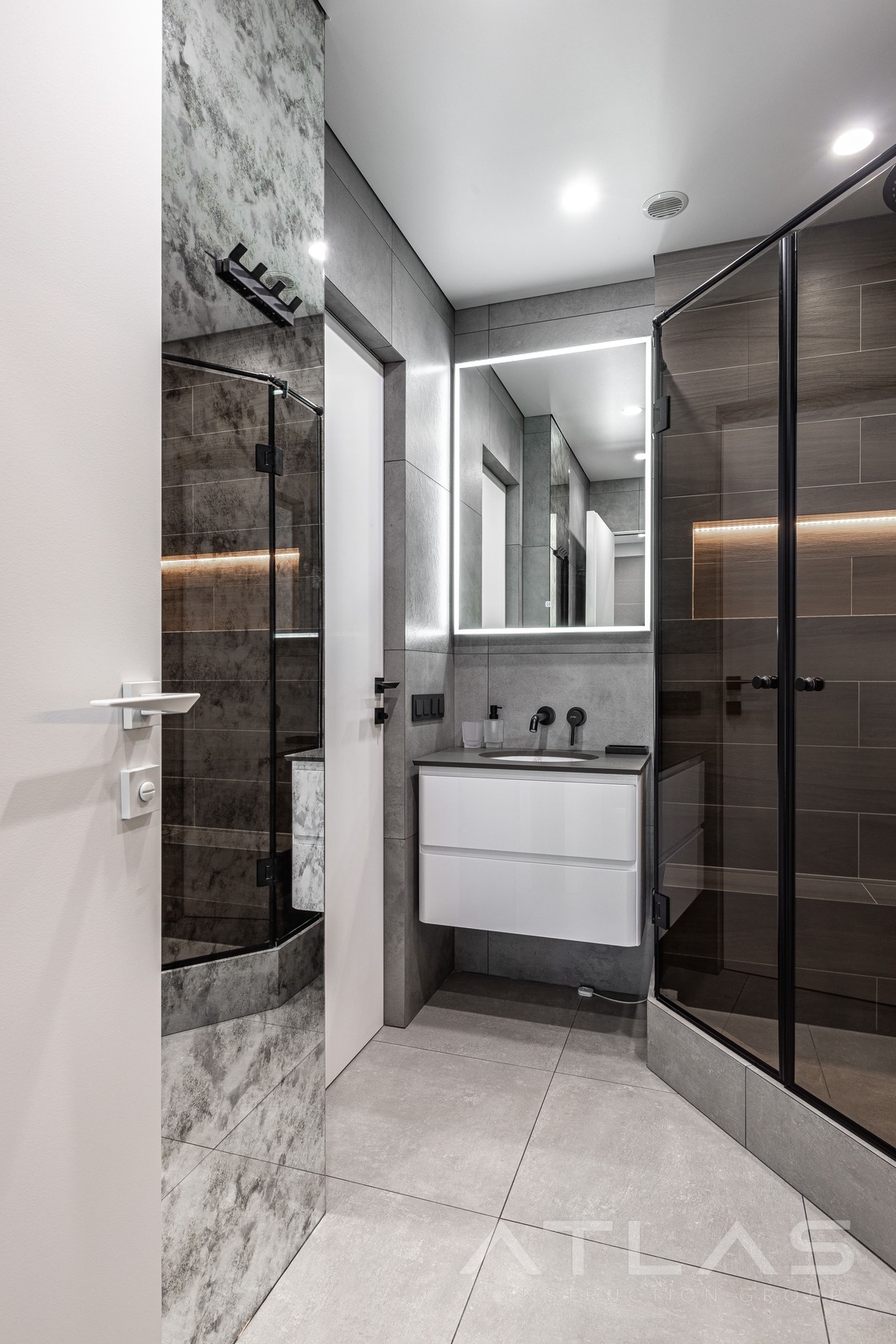 Contemporary bathroom renovation by ATLAS Construction Group with illuminated mirror and floating vanity